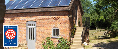 The red brick outbuilding known as the Byre, featuring solar panels on the roof and stone entry steps, overlaid with a VisitEngland 3-star logo.